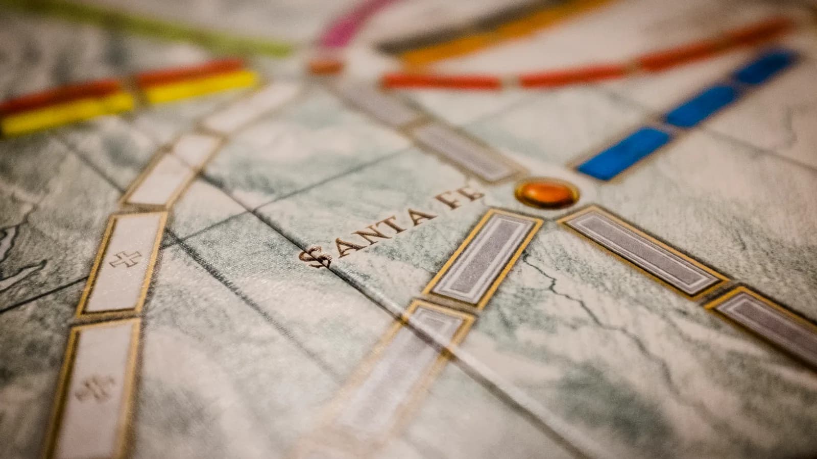 Gros plan sur le plateau du jeu de société Les Aventuriers du Rail, ville de Santa Fe entourée de routes ferrées colorées sur la carte des États-Unis