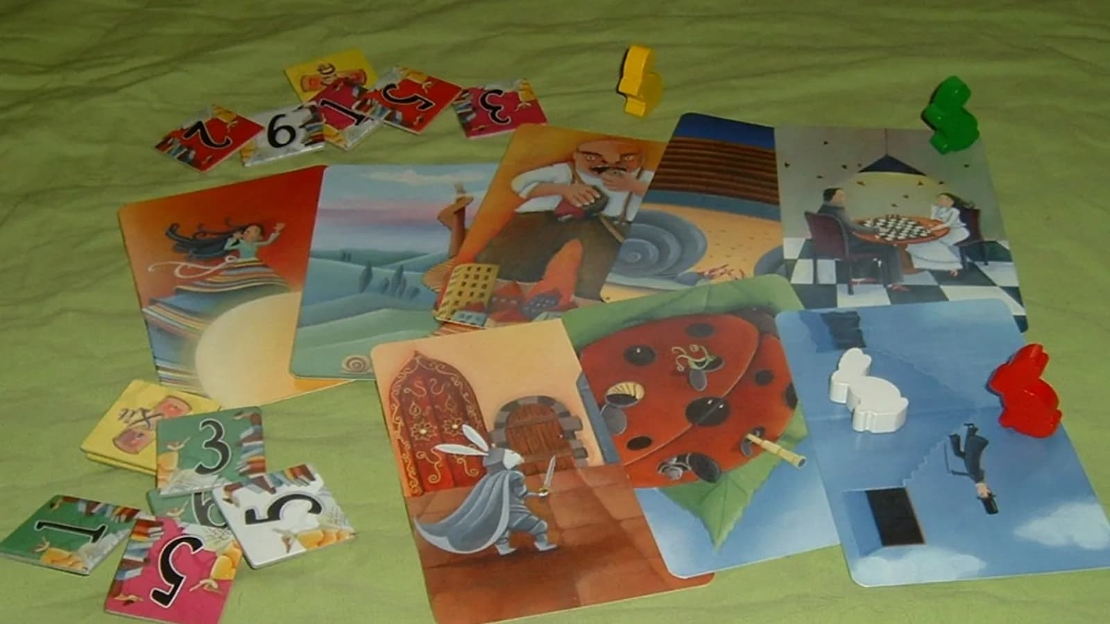 Cartes illustrées et pions lapins du jeu Dixit posés sur une table, avec les jetons de vote numérotés et plusieurs illustrations oniriques visibles