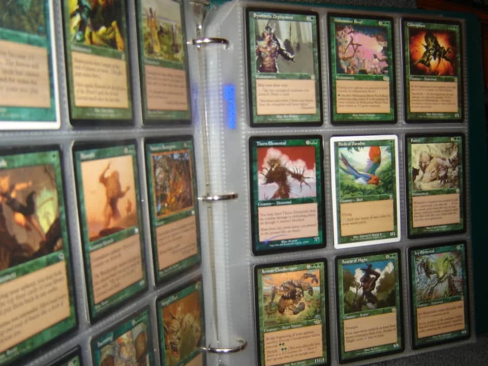 Classeur ouvert rempli de cartes Magic the Gathering vertes rangées dans des pochettes plastiques transparentes