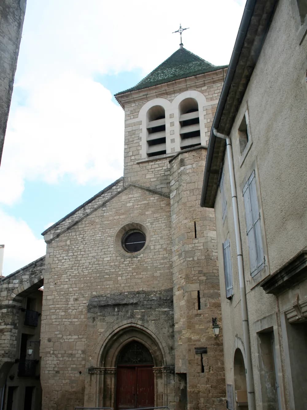 Façade en pierre de l'église gothique de Saint-Geniès-de-Fontedit, son clocher et son portail dans une ruelle du village