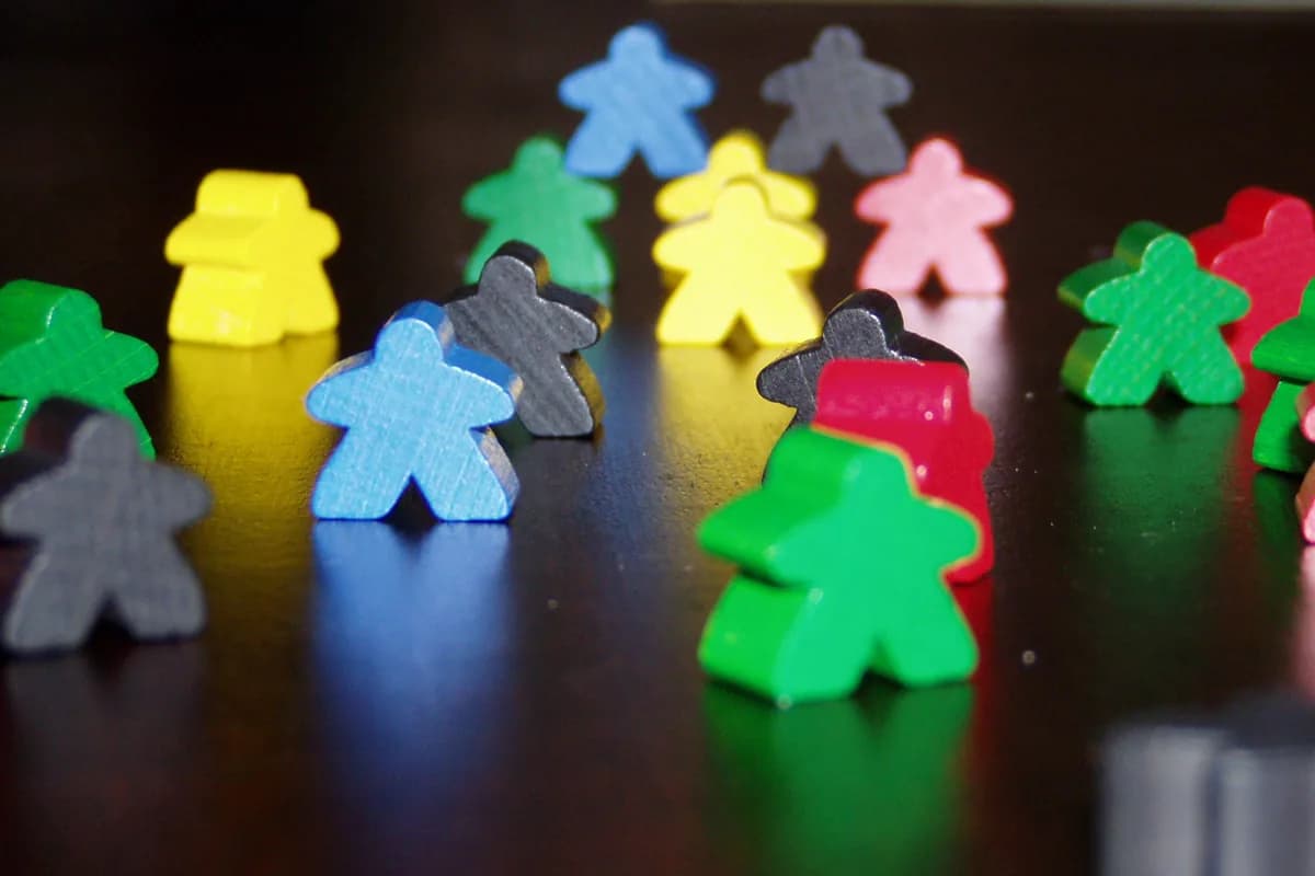 Sélection de meeples en bois rouge, jaune, vert, bleu et noir utilisés dans le jeu de société Carcassonne