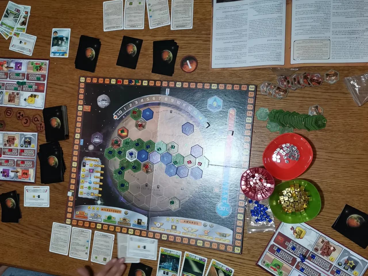 Partie de Terraforming Mars en cours : plateau central hexagonal de Mars, plateaux joueurs, cartes projet et coupelles de cubes de ressources
